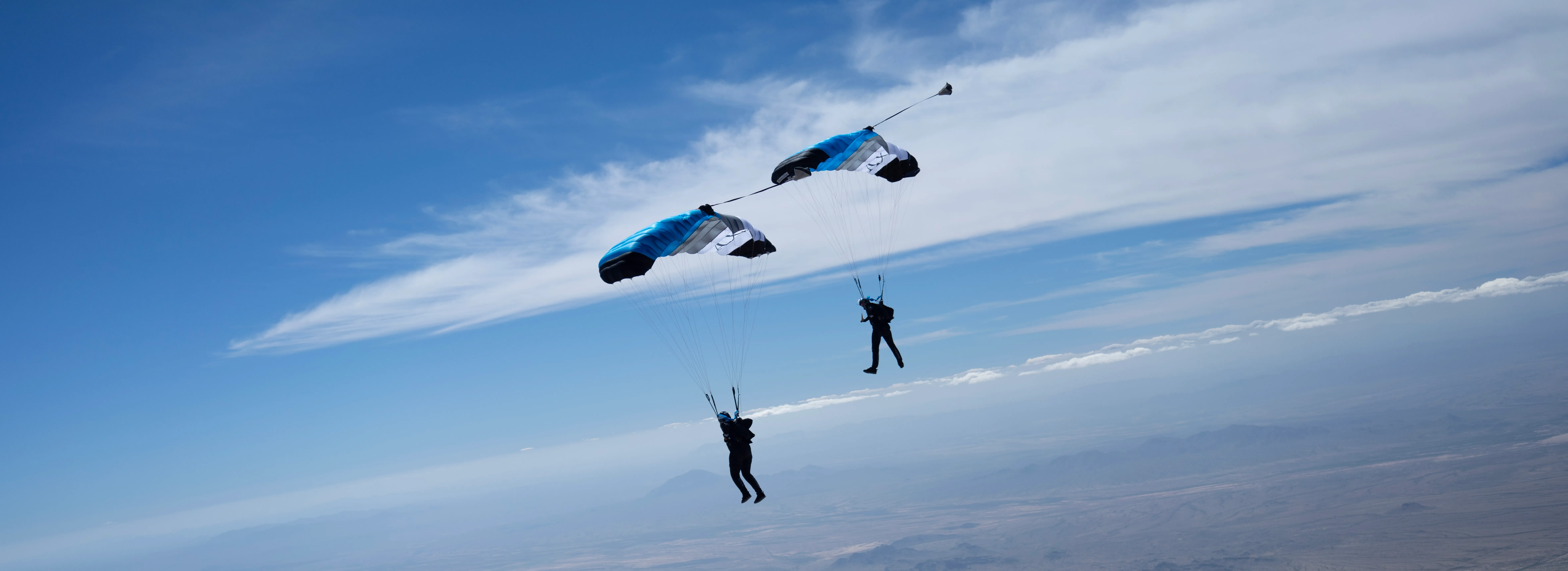 Two skydivers under parachutes